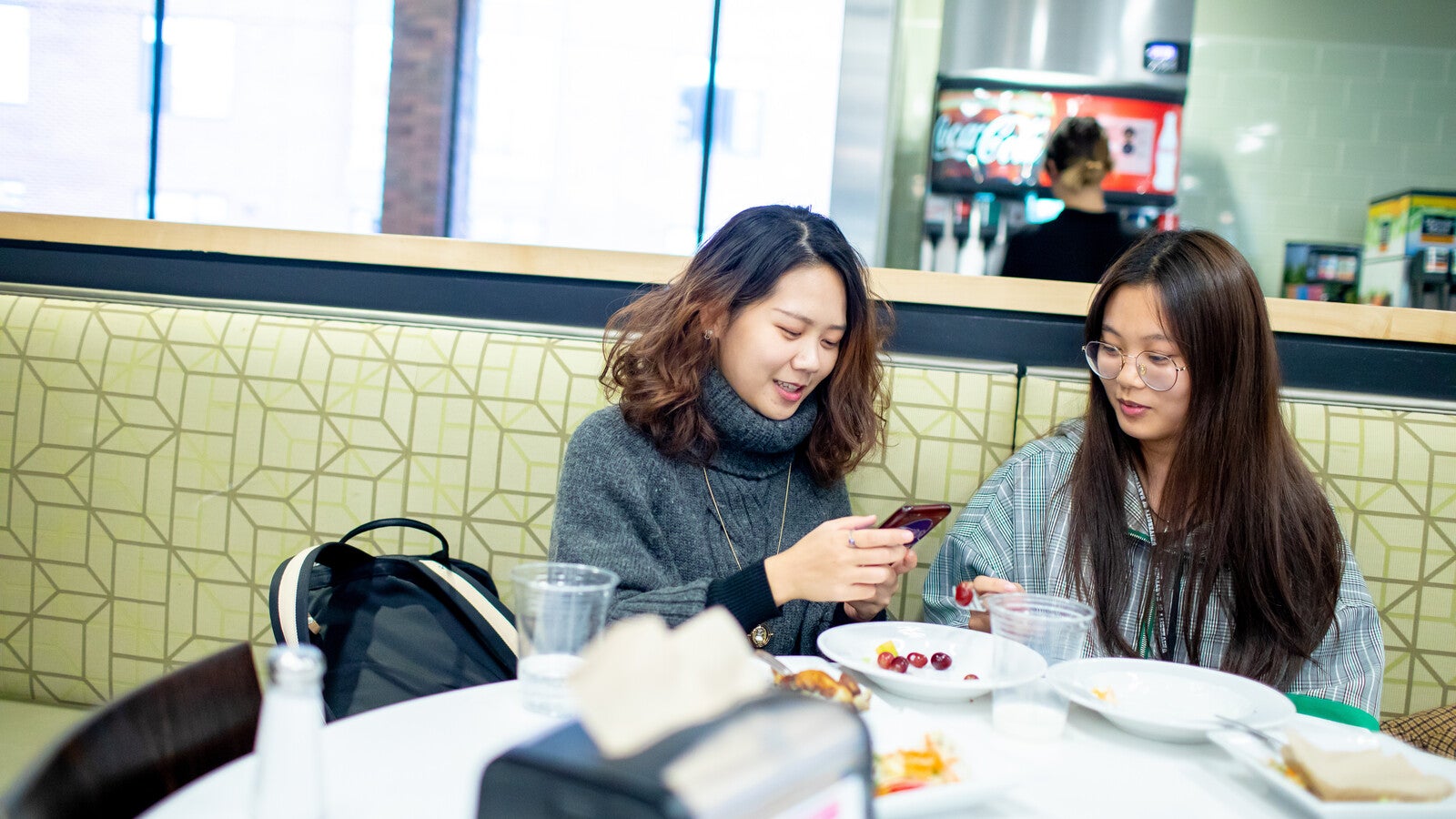 Students looking at phone in restaurant.