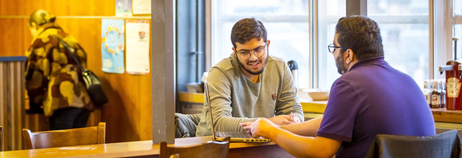 两名国际学生在使用笔记本电脑。