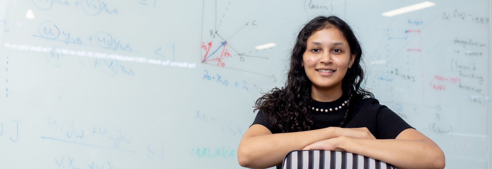 Student smiling in front of whiteboard