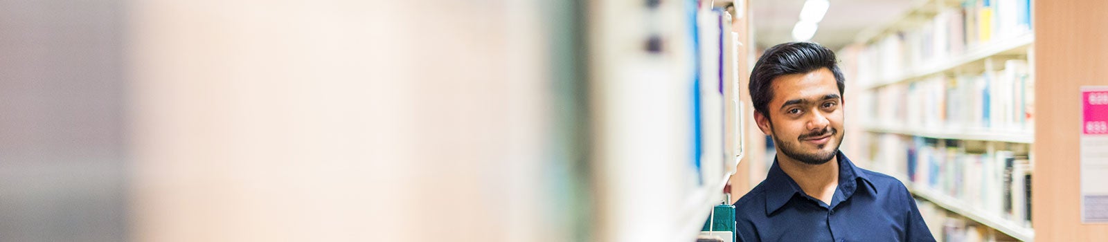 Student leaning against book shelves