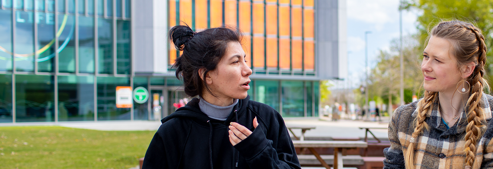 Students sitting on bench and talking outside campus