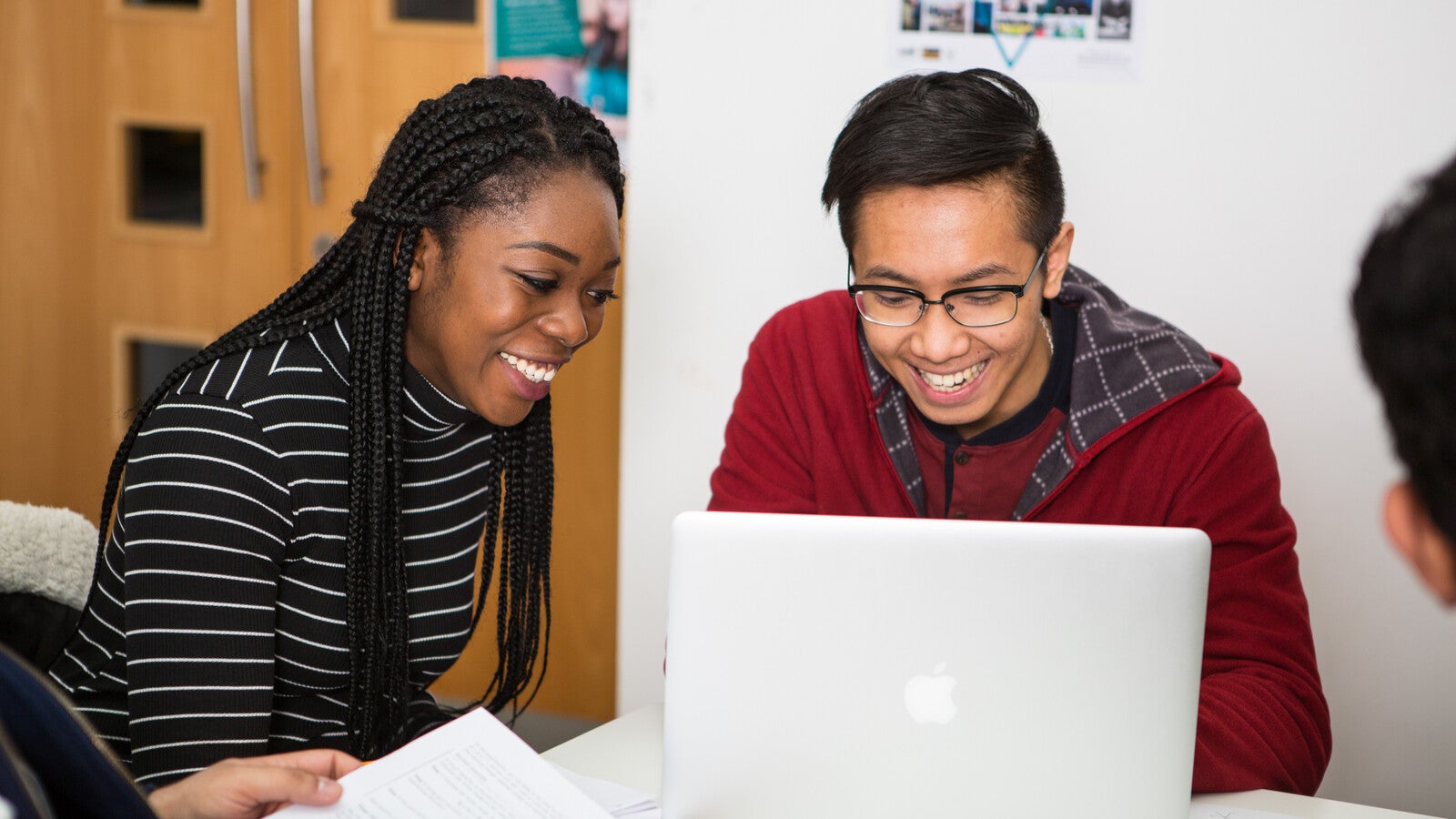 Two students looking at a laptop, smiling.