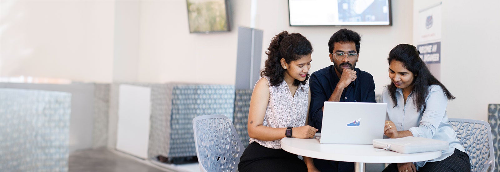 Three students working on a laptop
