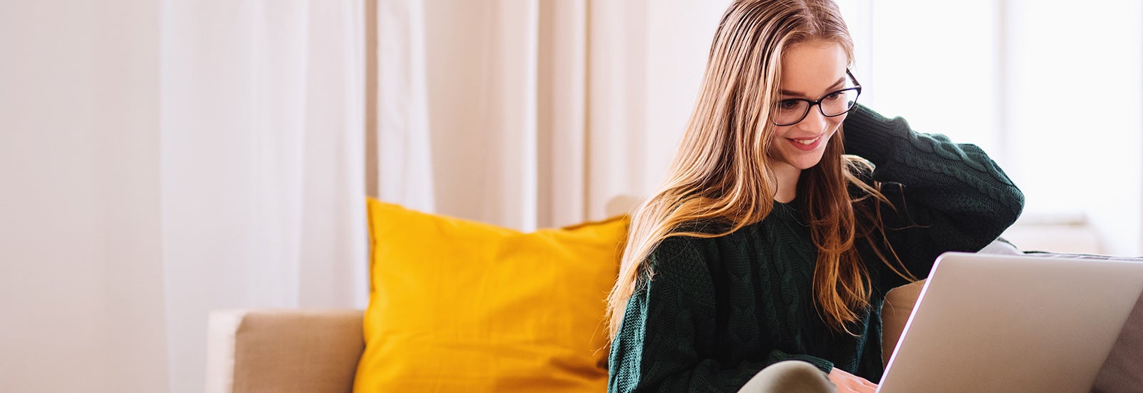 A student sitting on a sofa using a laptop