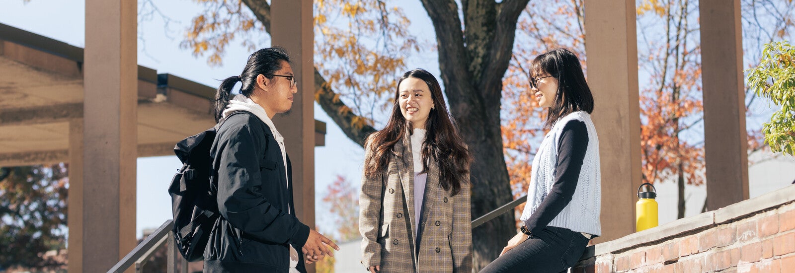 Three students talking outside on campus steps