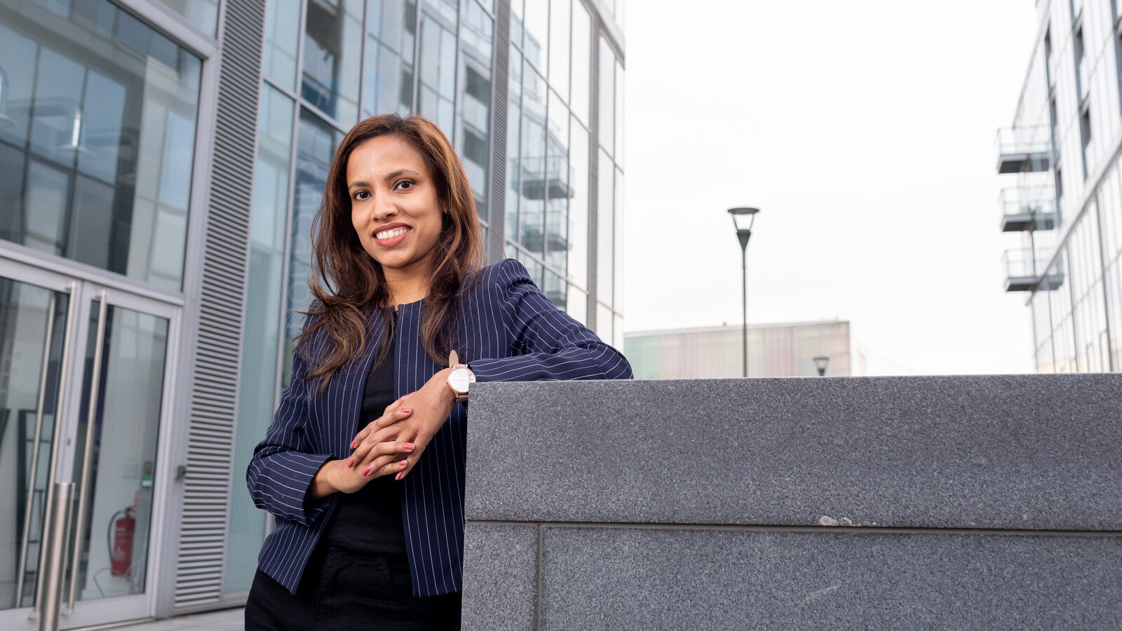 A female student smiling in front of campus buildings