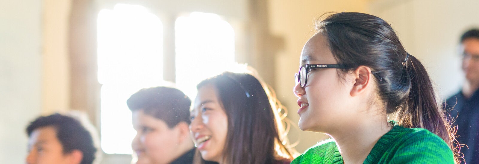 在教室里坐成一排面带微笑的学生