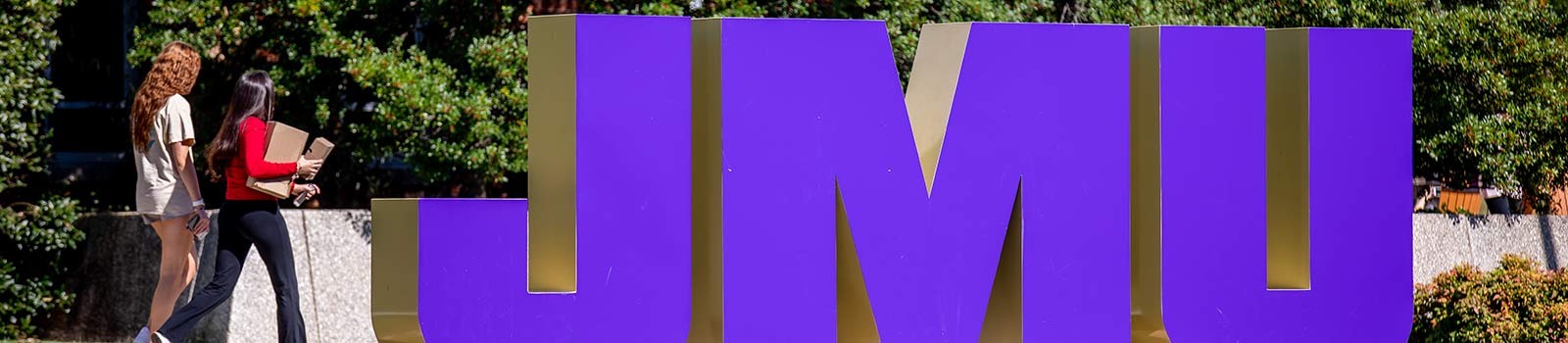 Students walking past JMU sign