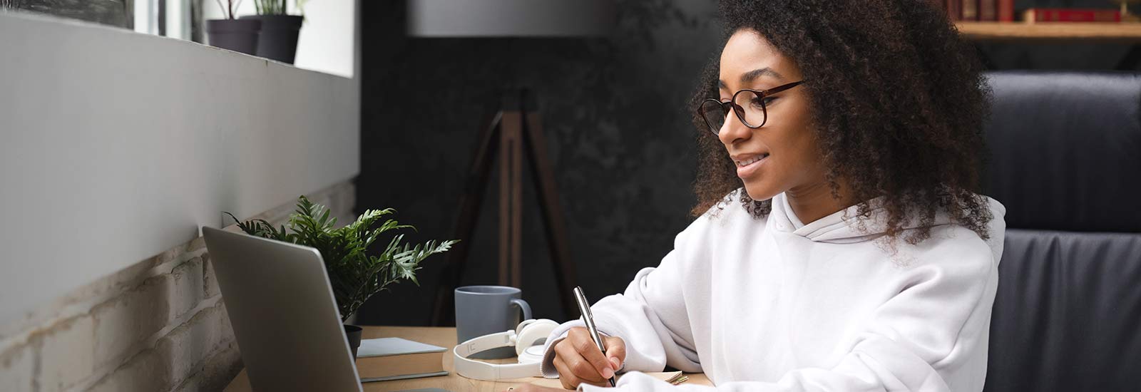 Student studying on laptop and writing notes