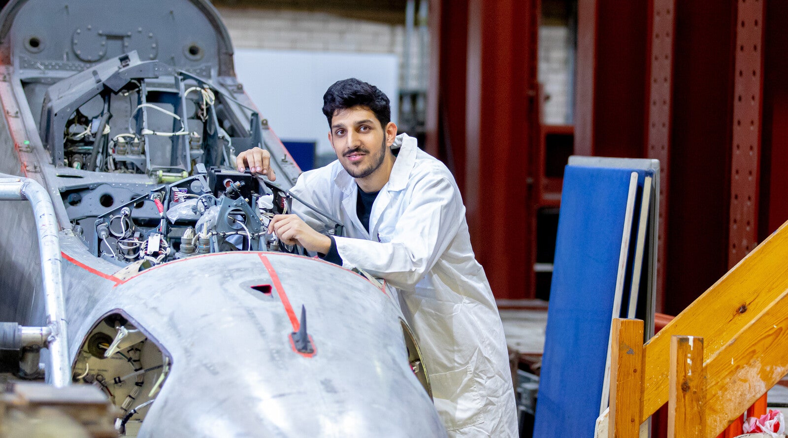Engineering student in a lab coat working on an engine.