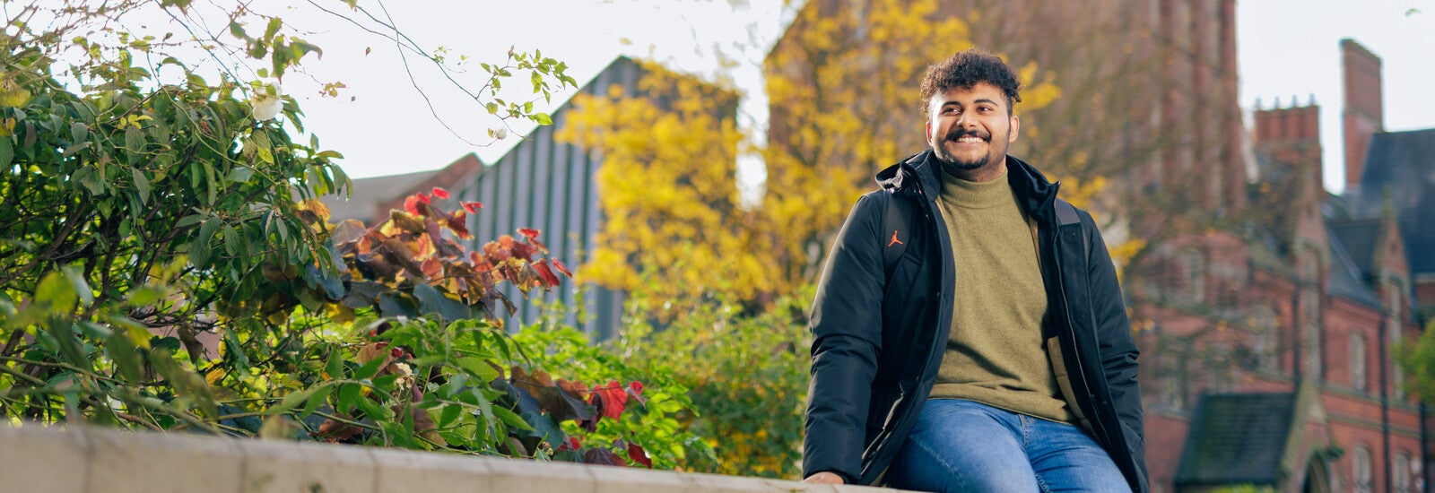 Teesside student sitting on wall outside campus