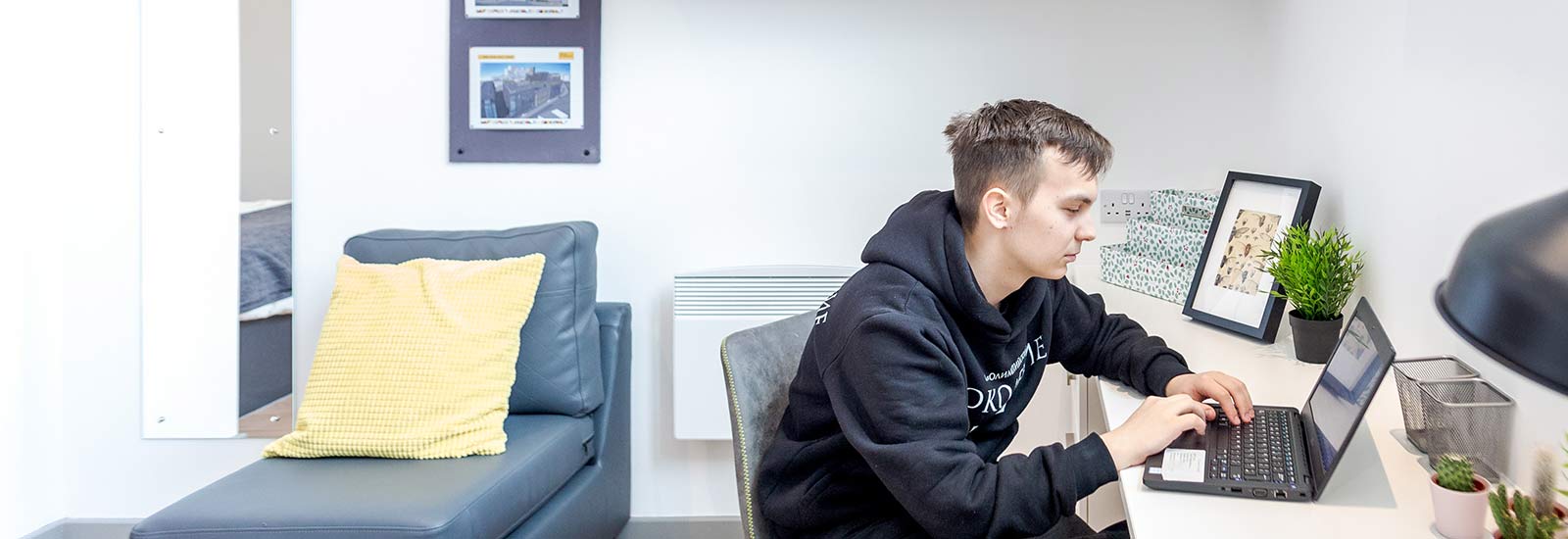 A student sat at a desk using a laptop