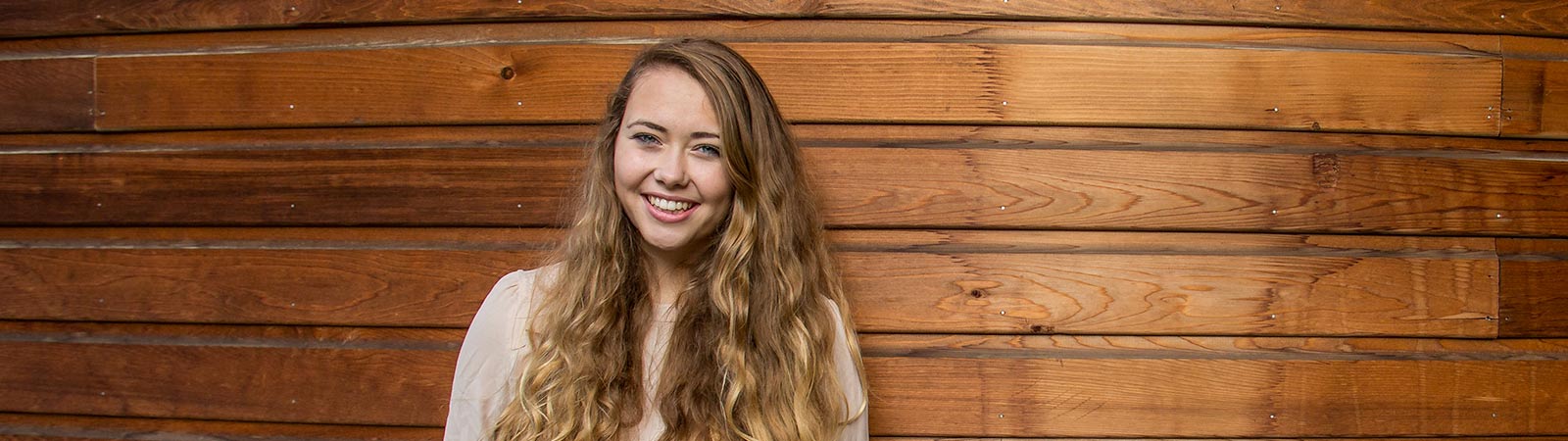 Student smiling and leaning against wall