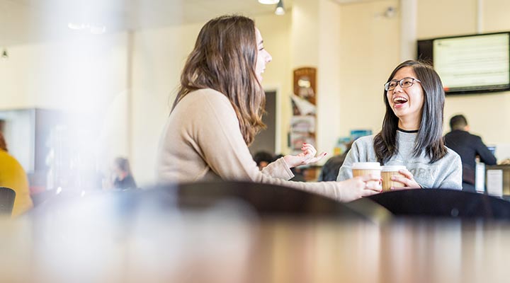 Students laughing at a table together in a coffee shop