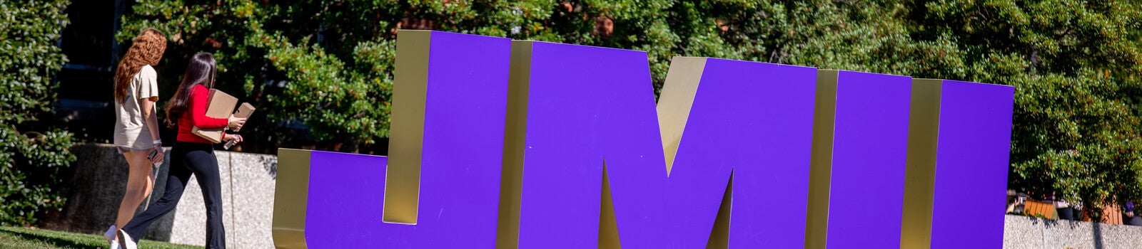 Students walking past JMU sign