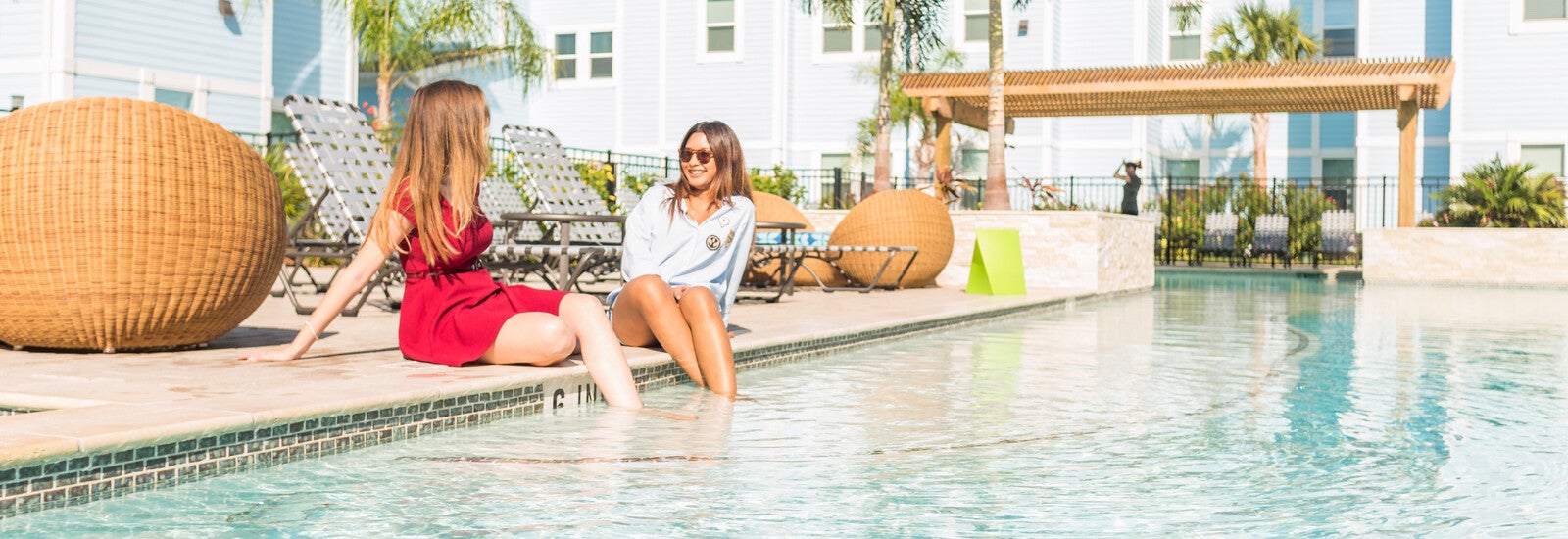 Students sitting by pool with their feet in the water