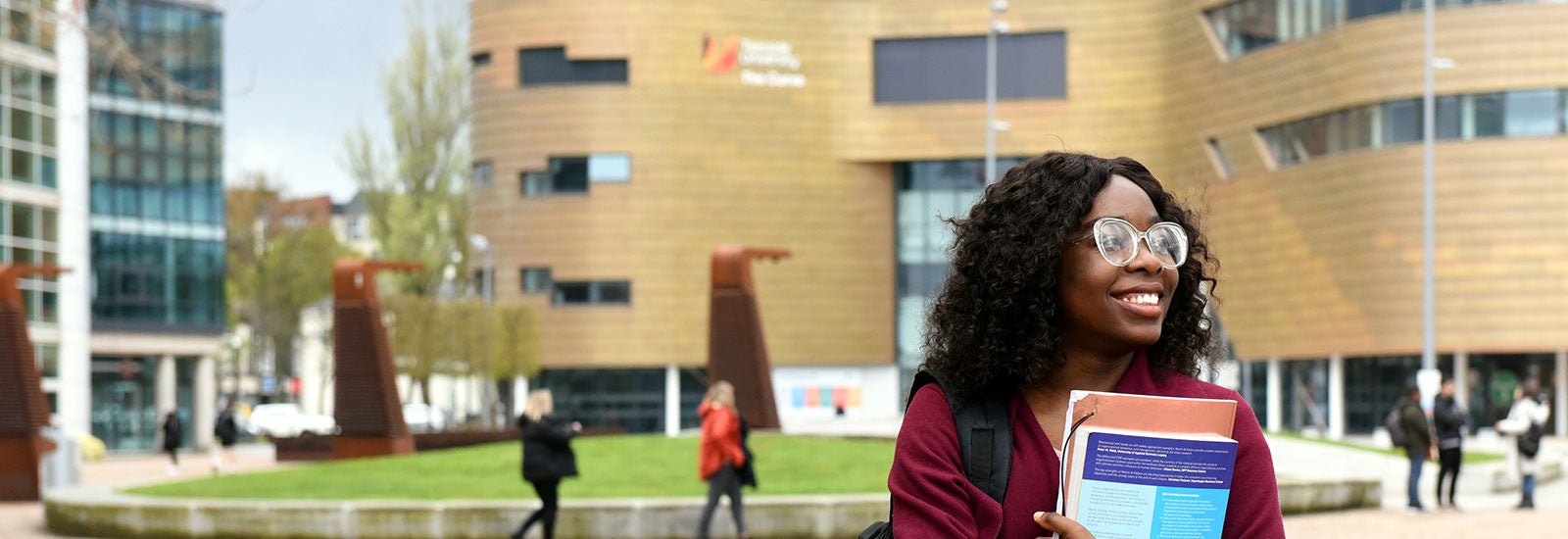 Student holding books outside campus