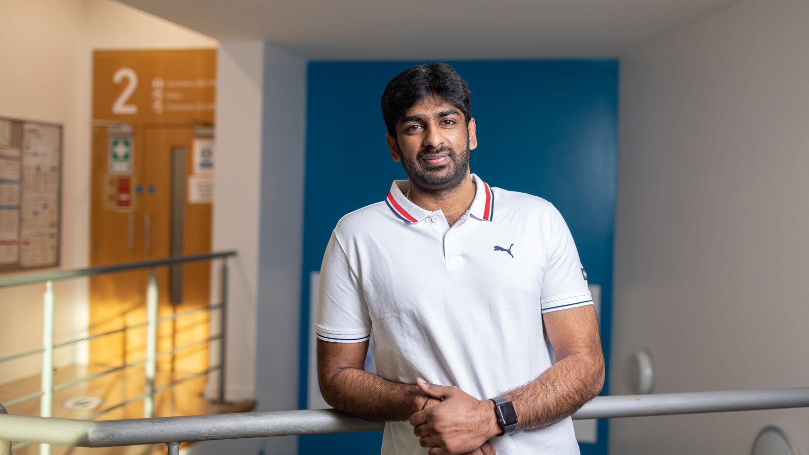 A student leaning against railing on campus