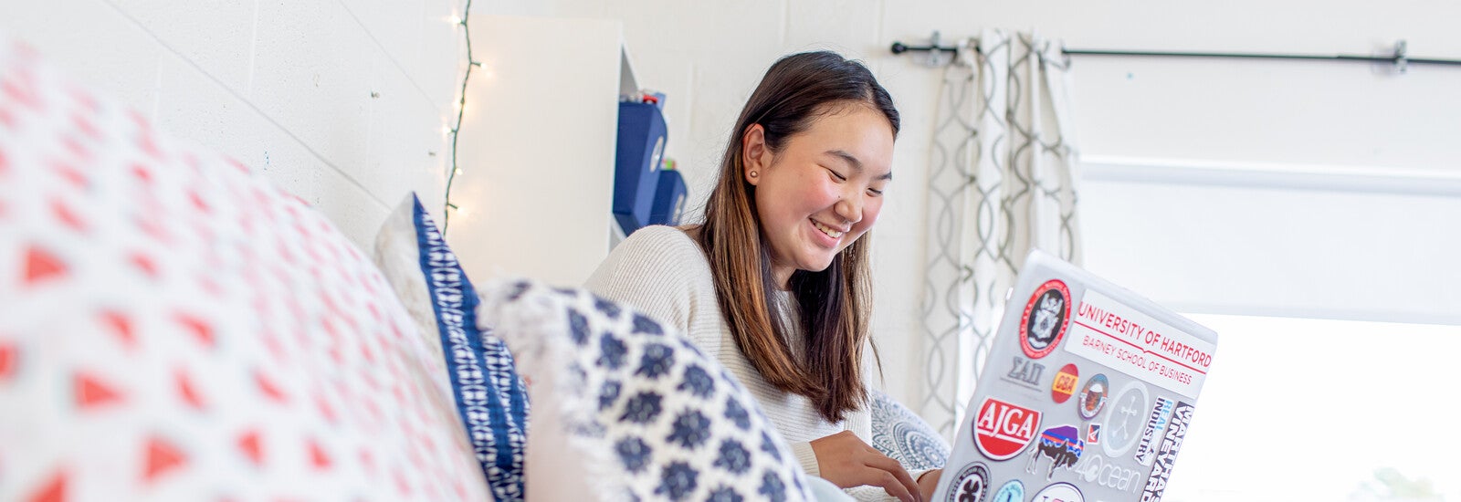 A student using a laptop in a bedroom