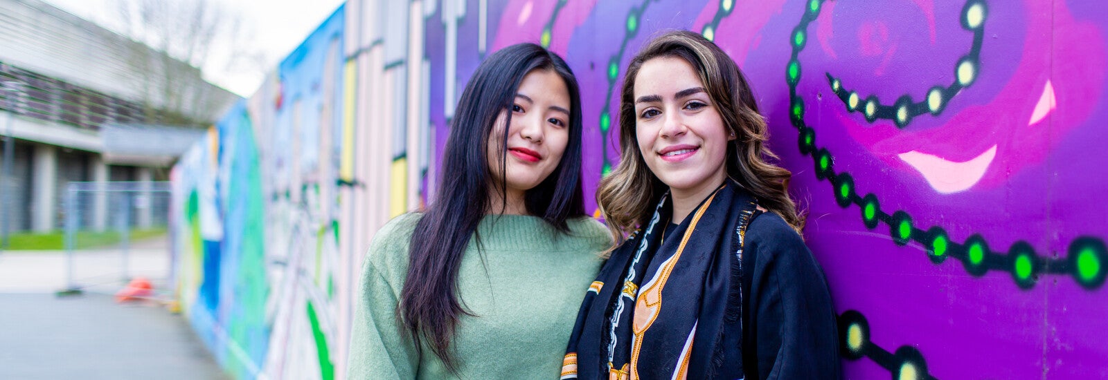 Students smiling by wall of street art