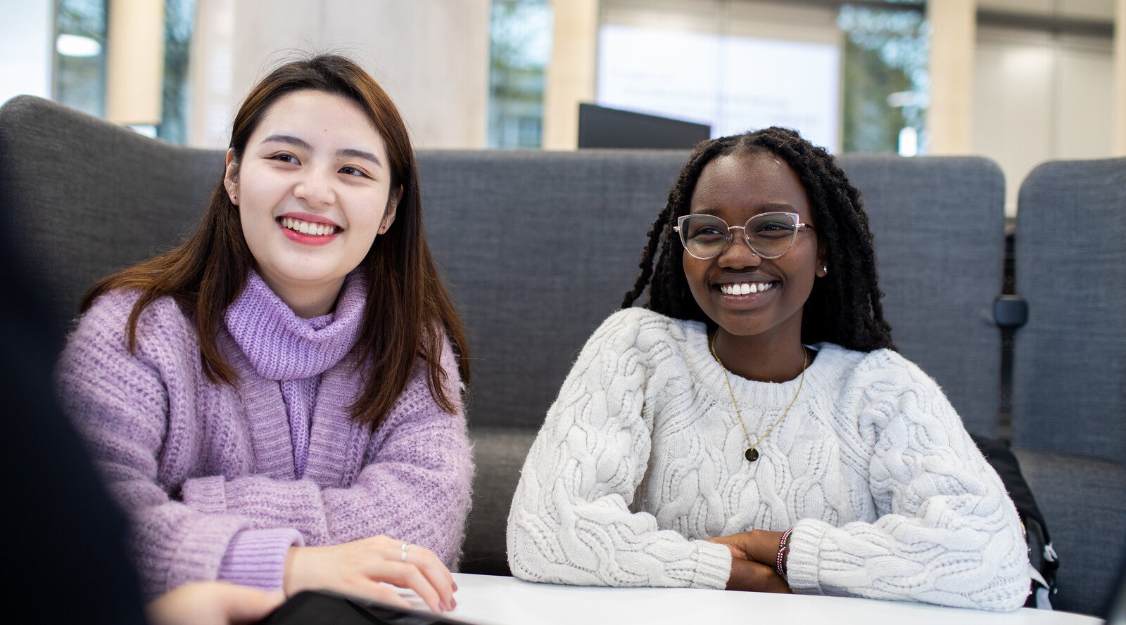 Students smiling and sitting in front of sofa