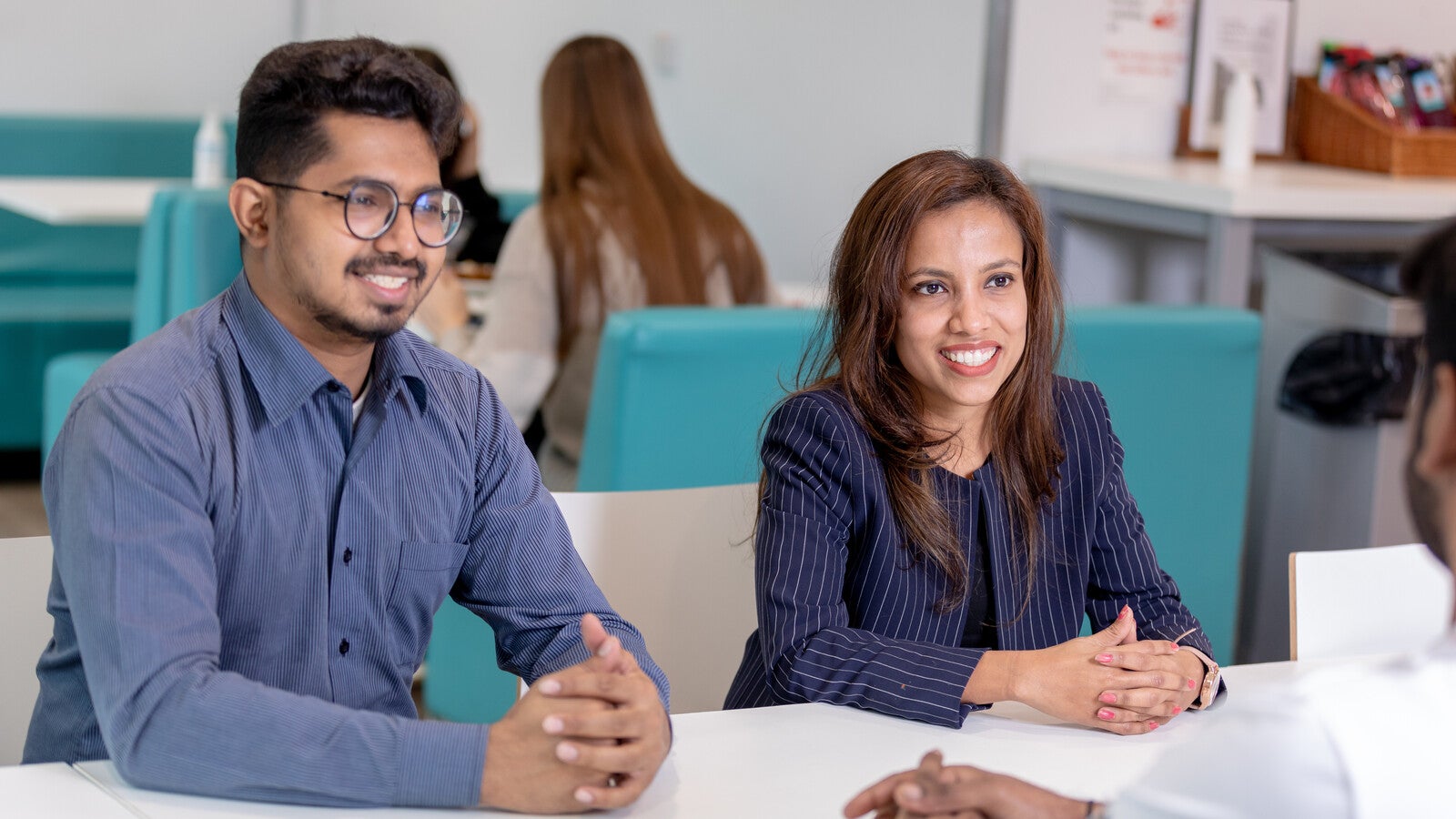 Two students smiling at a table on campus