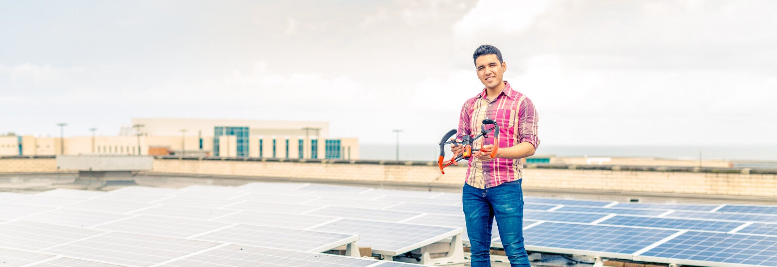 Student standing on rooftop holding drone