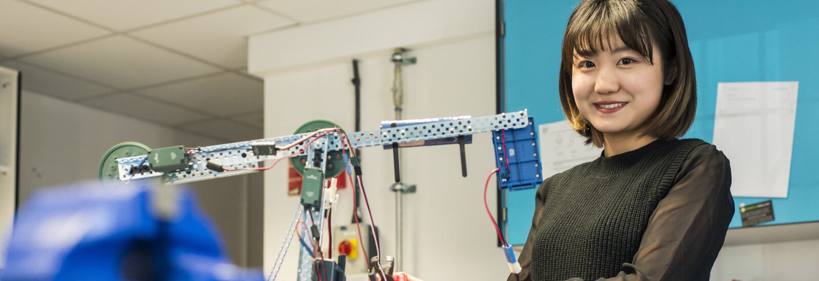 Student smiling at camera while holding model