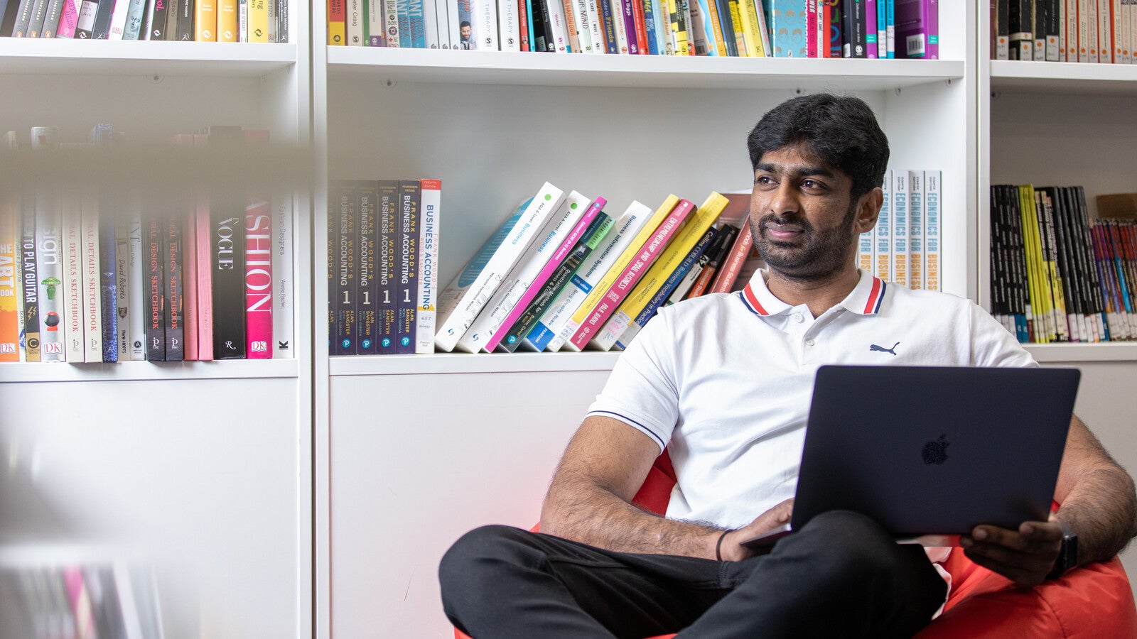 A student sitting on a beanbag and using a laptop