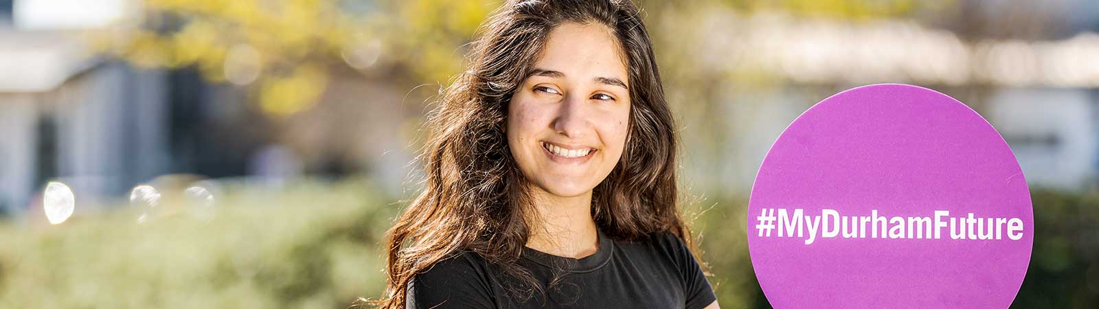 Student smiling and holding Durham sign