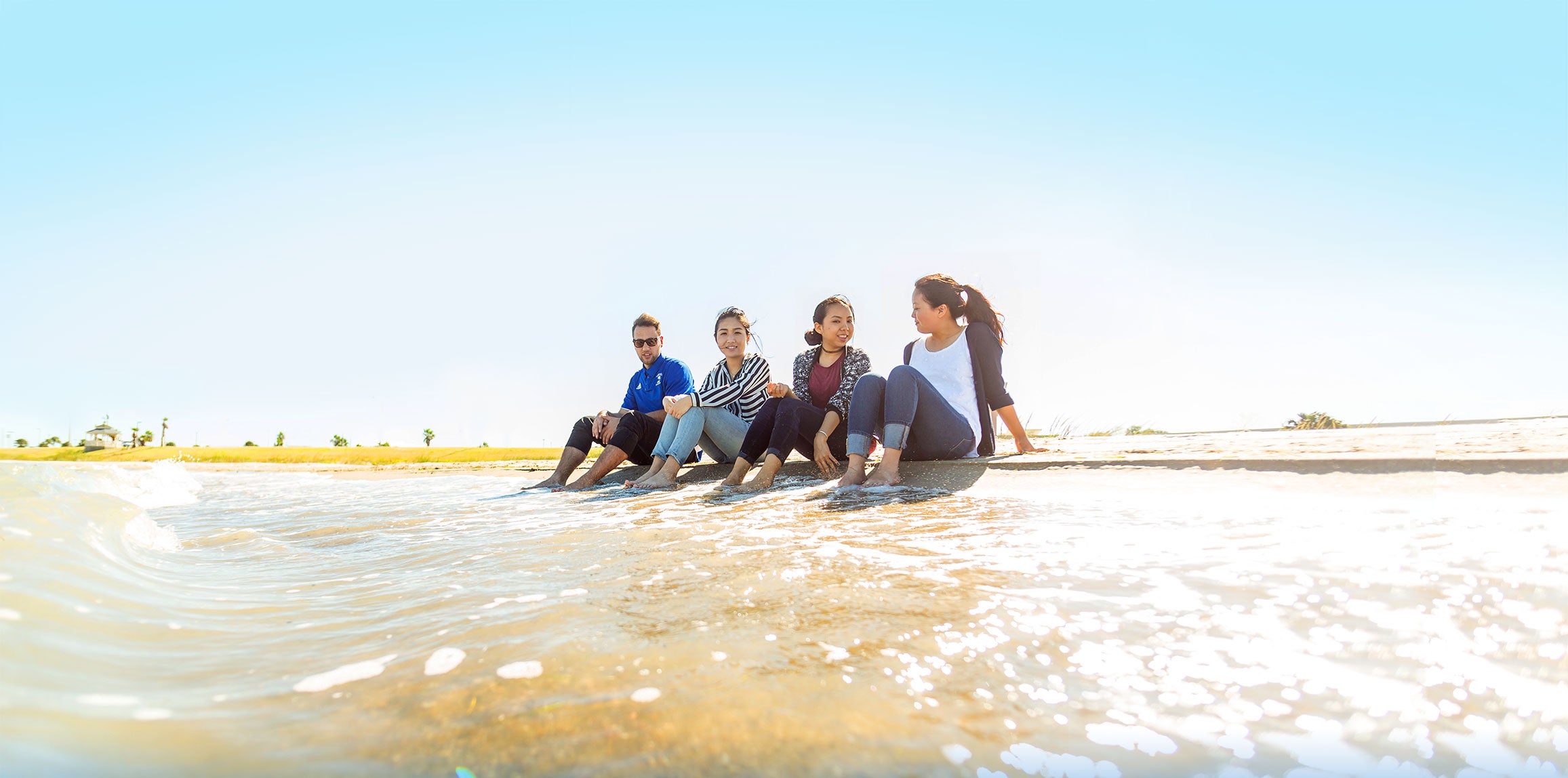 Students sitting on beach together with toes in the sea