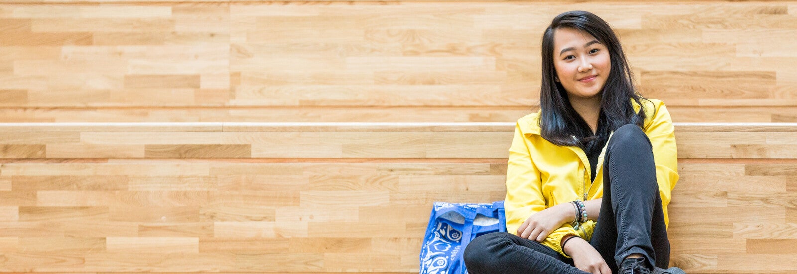 Student smiling and sitting on wooden lecture bench