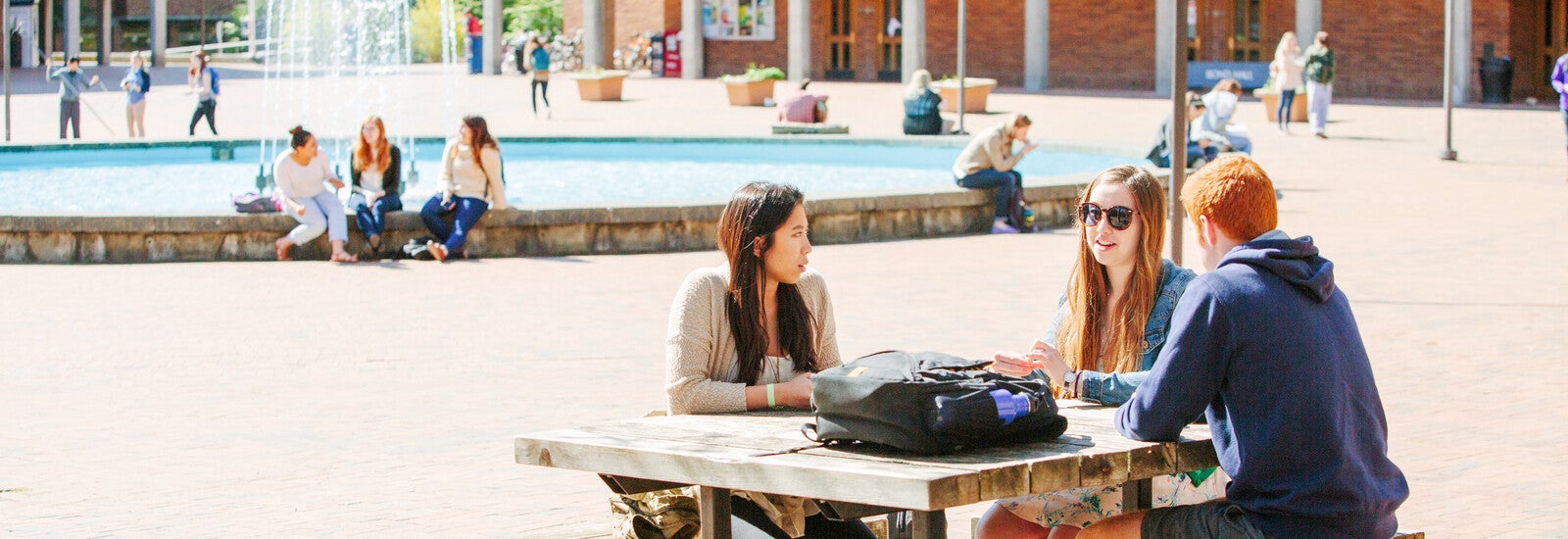 A male student sitting outside working on a laptop.