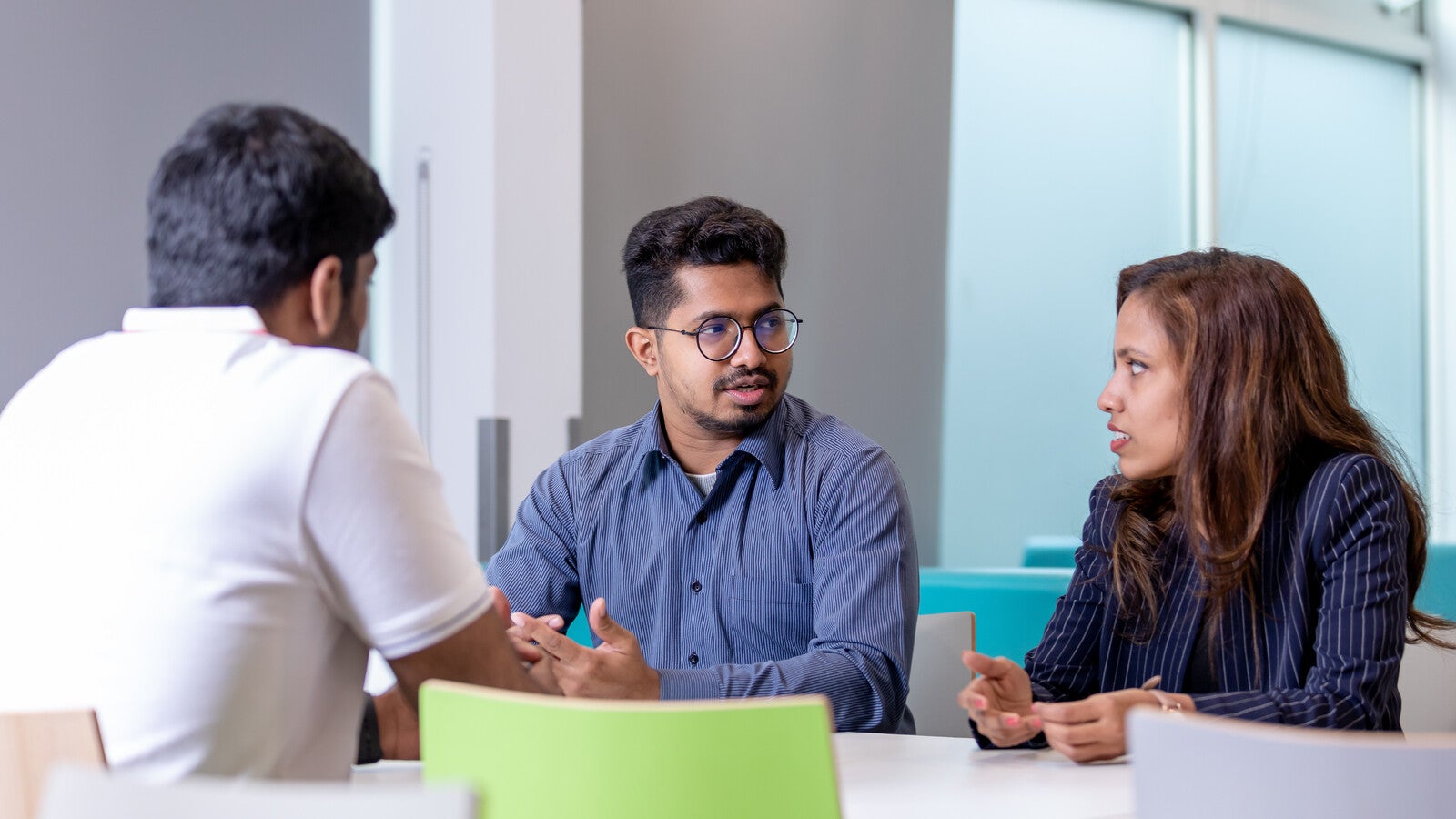 Three students sitting at a table on campus and talking