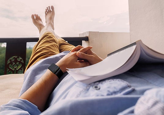 A man relaxes with a book on his chest. 