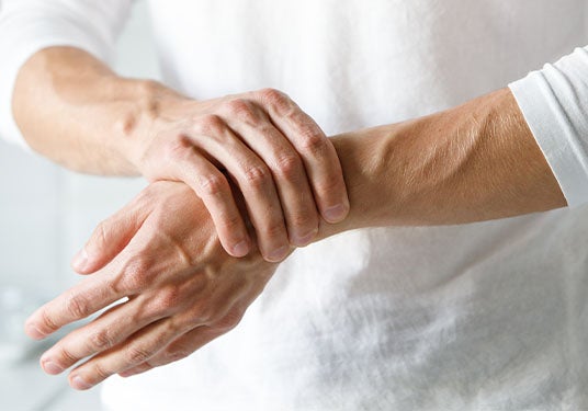 Close-up of man holding wrist with arthritis and joint inflammation