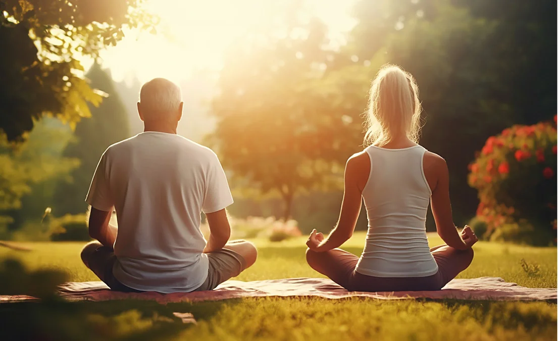 A man and woman doing yoga in the sunshine.