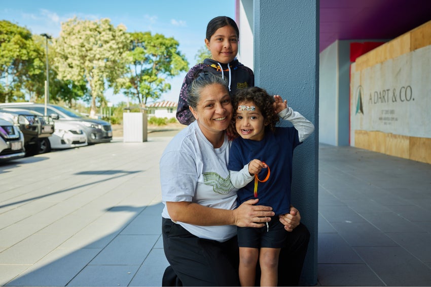 A First Nations woman poses for a photo with her two young daughters.