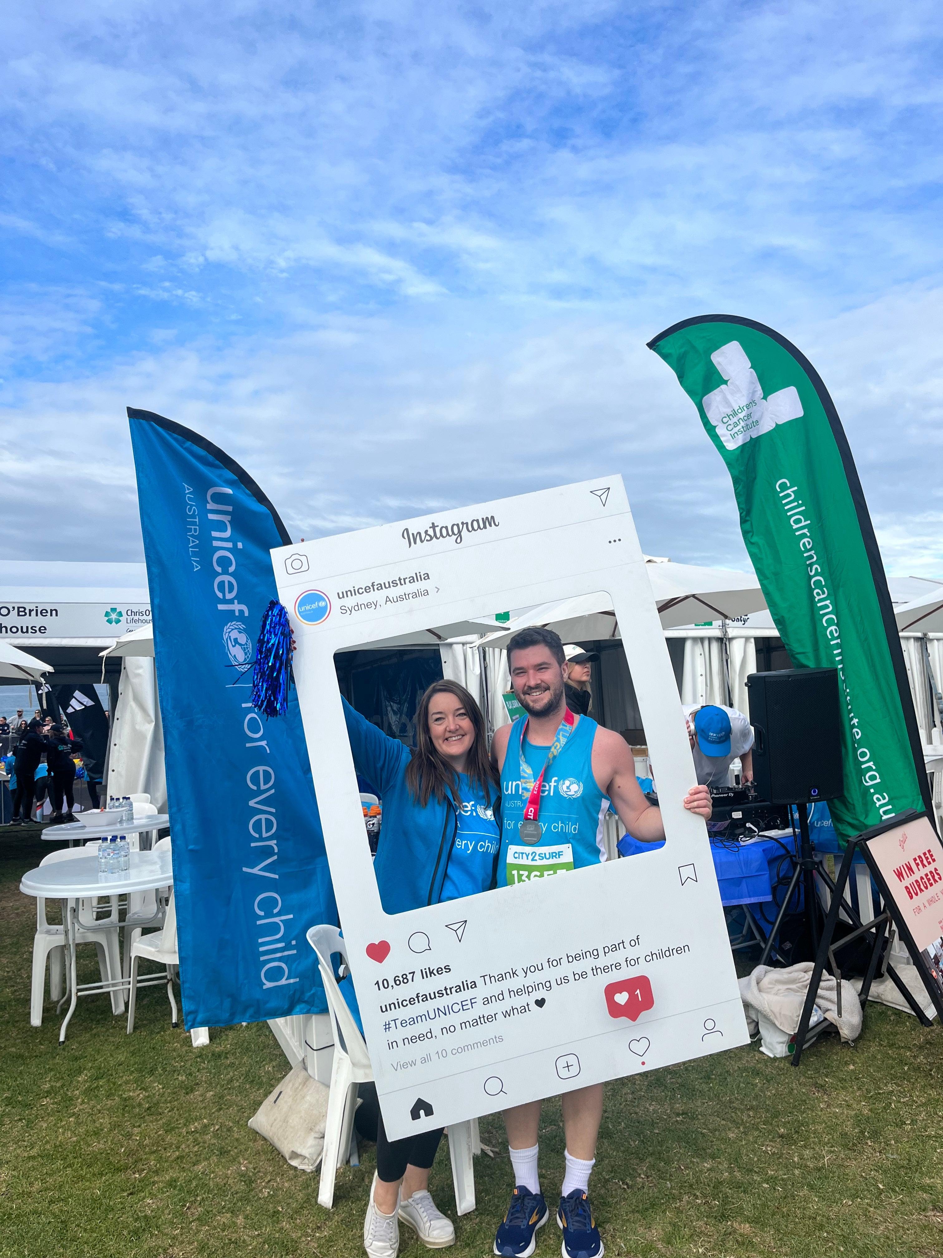 A man and woman smile while holding a UNICEF photo frame.