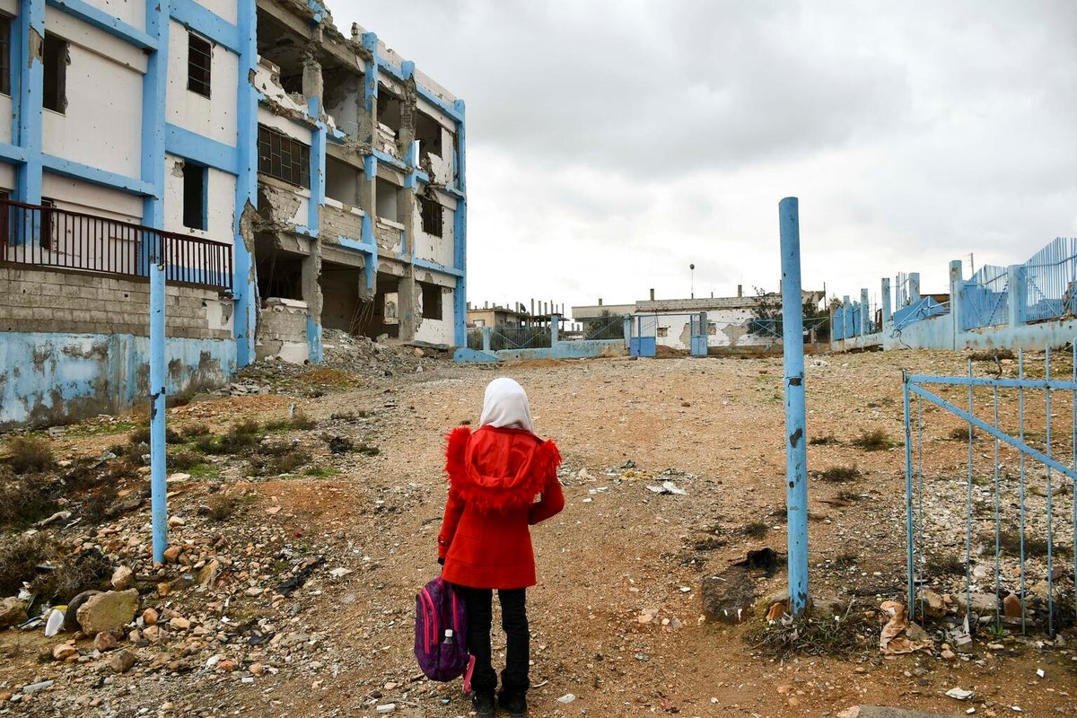 A girl stands in front of an empty lot. 