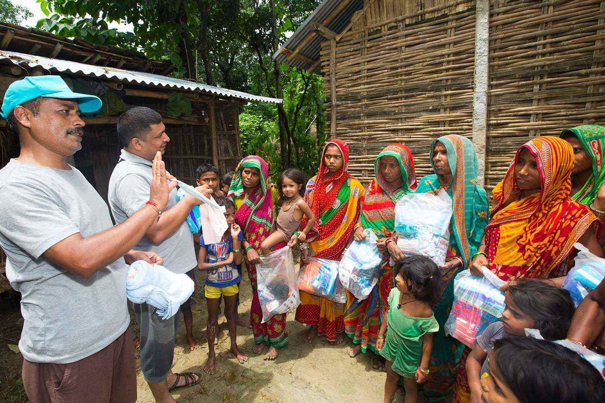 A group of women listens to a UNICEF worker who is explaining something.