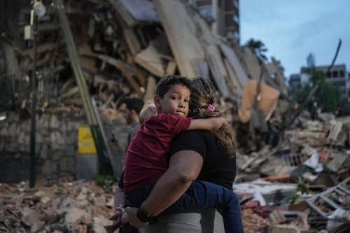 A mother holds a child amid the rubble caused by the Venezuela earthquakes