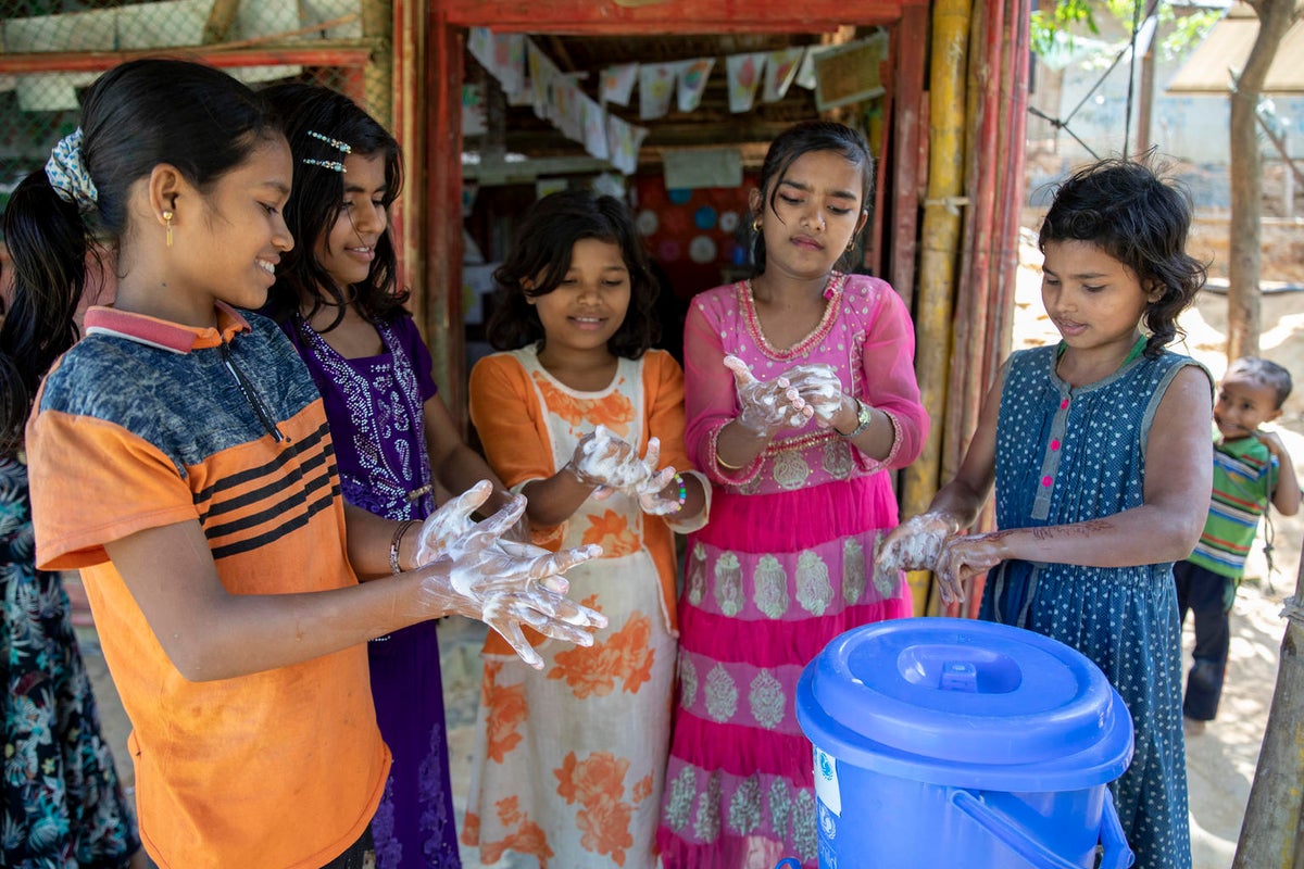 A group of girls are washing their hands with soap.