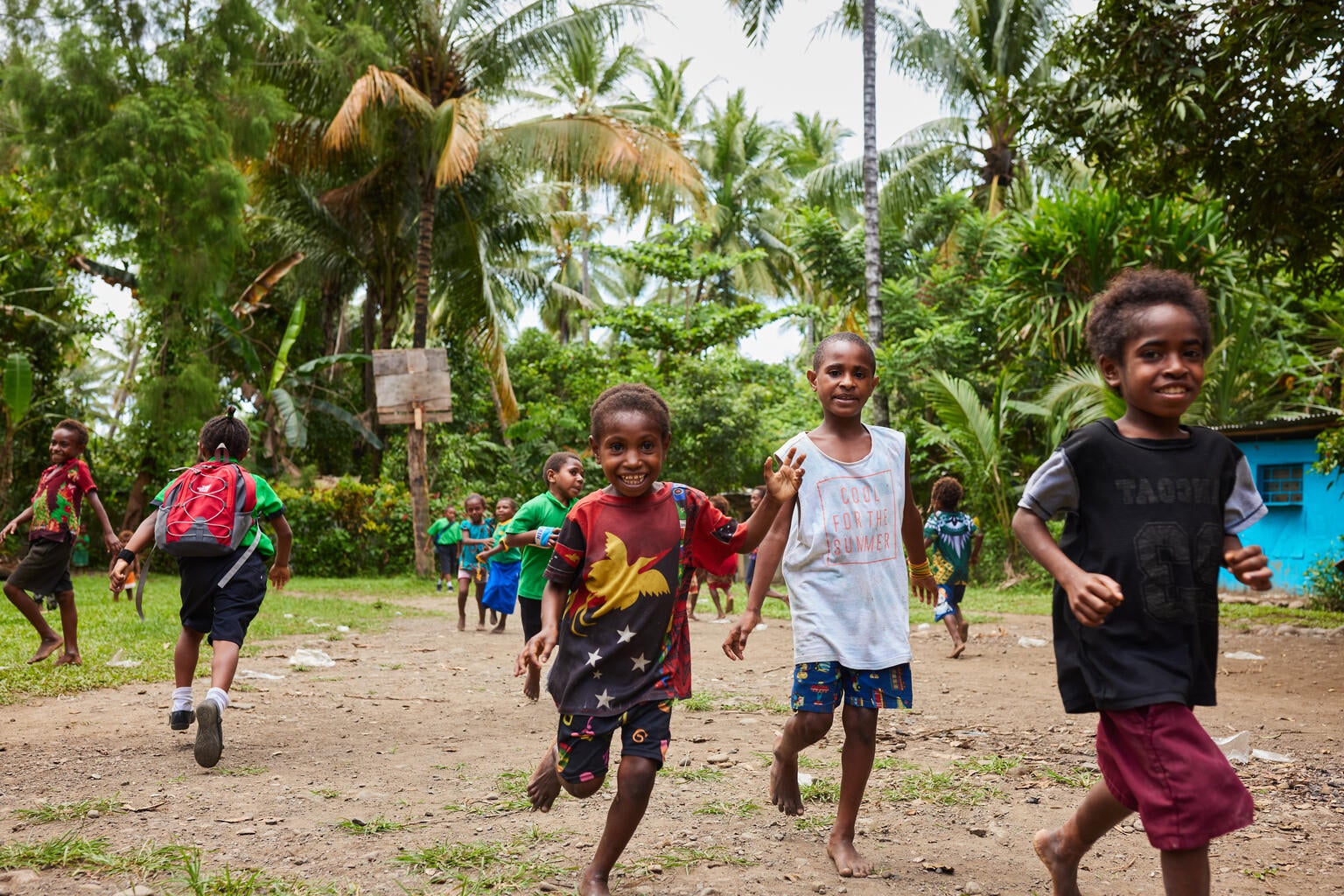 A group of children run towards the camera and smile.