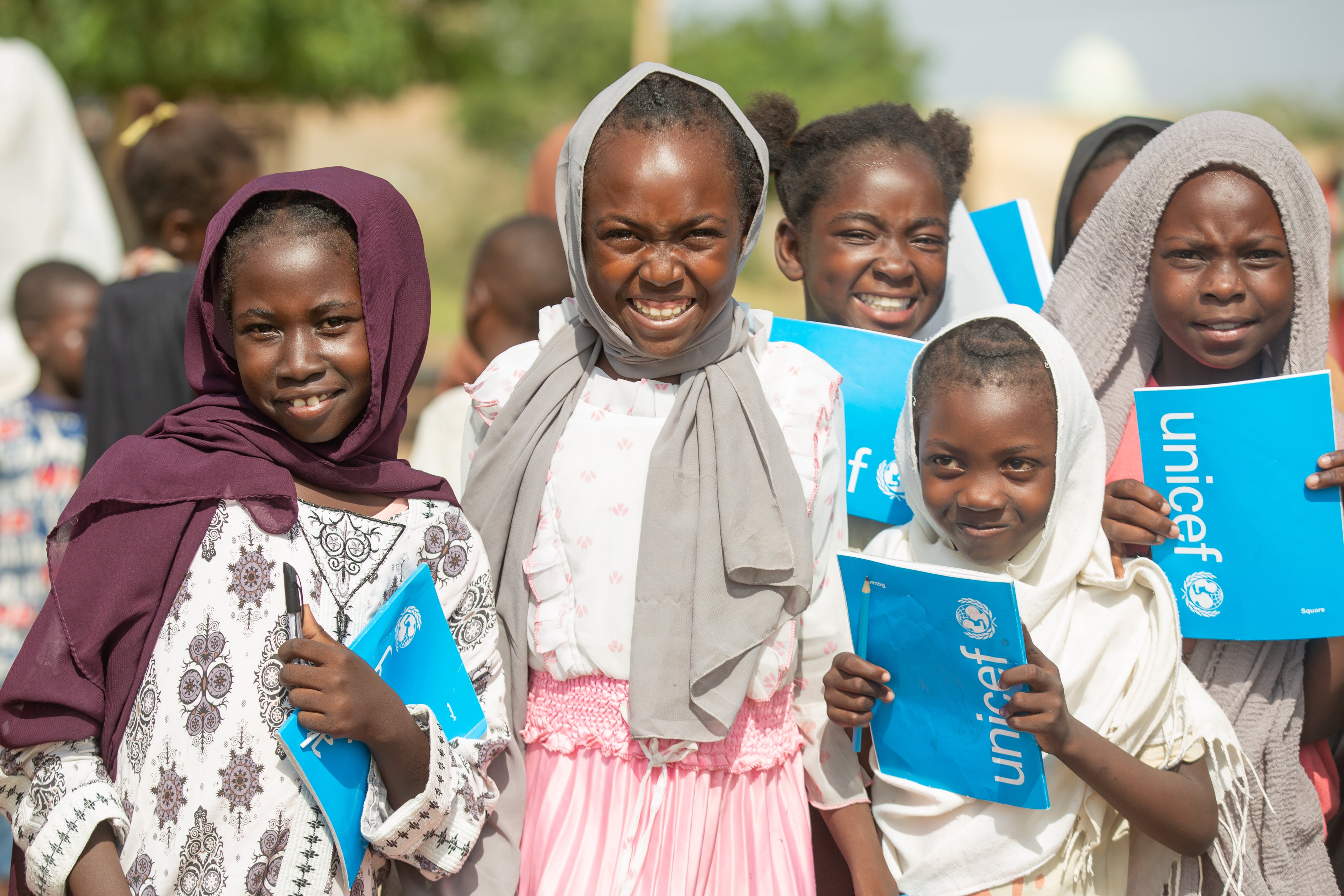 Displaced children with UNICEF exercise books at a safe learning space in Sudan.
