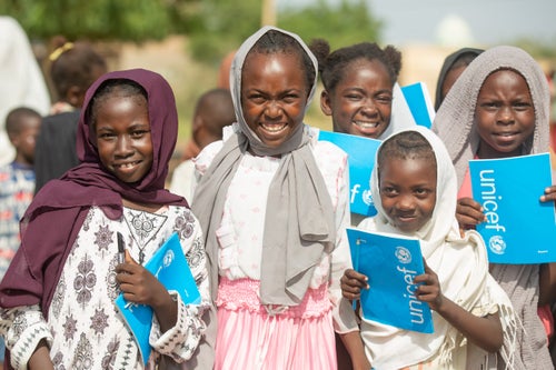 Displaced children with UNICEF exercise books at a safe learning space in Sudan.