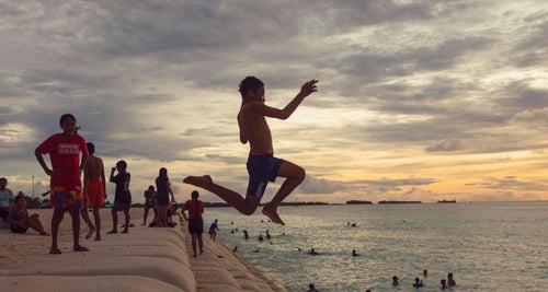 A young boy jumps from a sandbag staircase into the sea in Tuvalu.