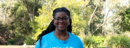Princess poses for a photo in bushland wearing a blue UNICEF Australia shirt