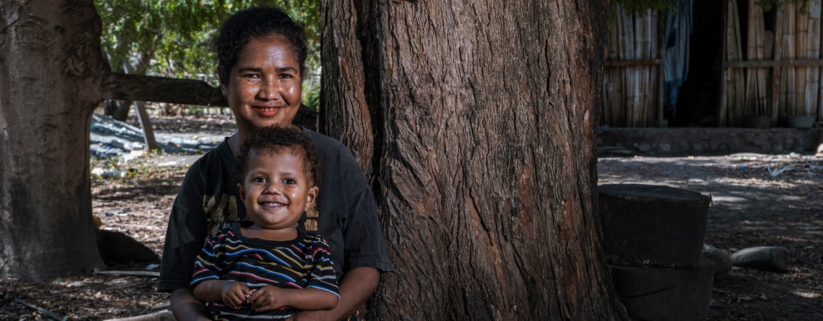 Mother and child sitting under the shade of a tree.