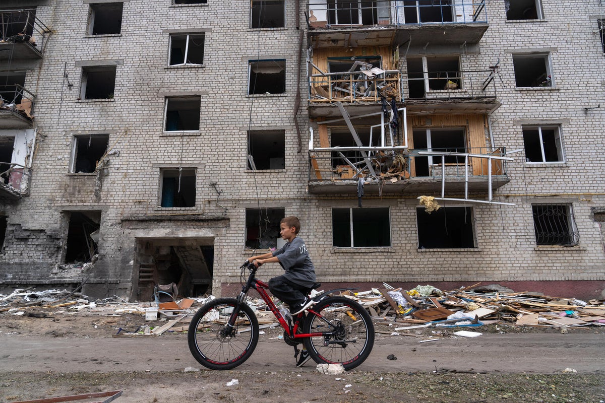 A boy rides his bicycle past a residential building heavily damaged during an overnight attack in Kyiv, Ukraine.
